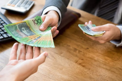 Hands exchanging Australian cash on a desk, representing fast same-day payouts for car pawn loans with E-Pawn Sydney